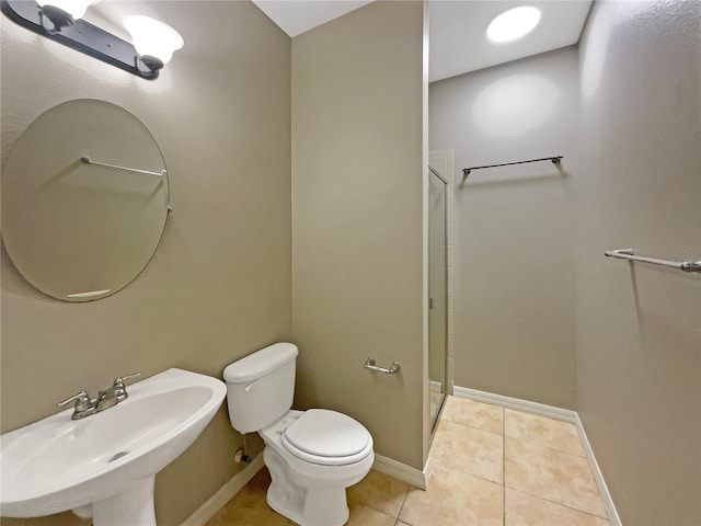 bathroom featuring toilet, tile patterned flooring, baseboards, and a sink