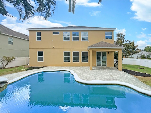 rear view of property with a fenced in pool, fence, a patio, and stucco siding