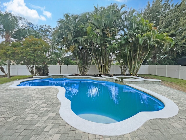 view of pool featuring a patio, a fenced backyard, and a pool with connected hot tub