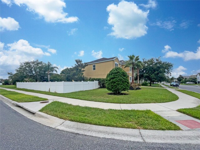 view of side of property featuring a yard, fence, and stucco siding