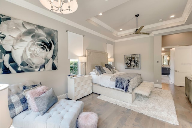 bedroom featuring light wood-type flooring, a tray ceiling, ornamental molding, and baseboards