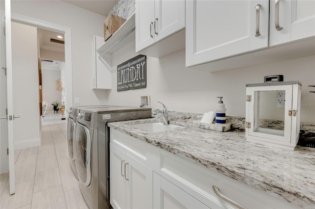 laundry area with washing machine and dryer, cabinet space, and a sink