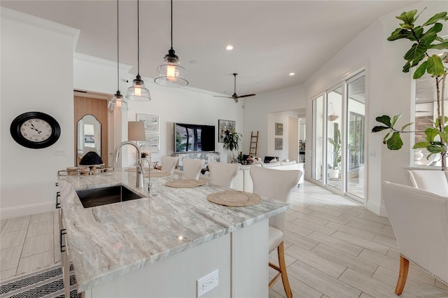 kitchen featuring recessed lighting, hanging light fixtures, wood tiled floor, a sink, and baseboards