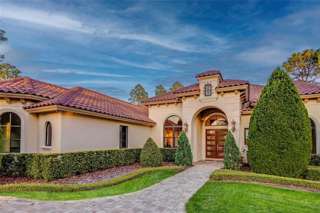 mediterranean / spanish-style home featuring stucco siding, a tiled roof, and french doors