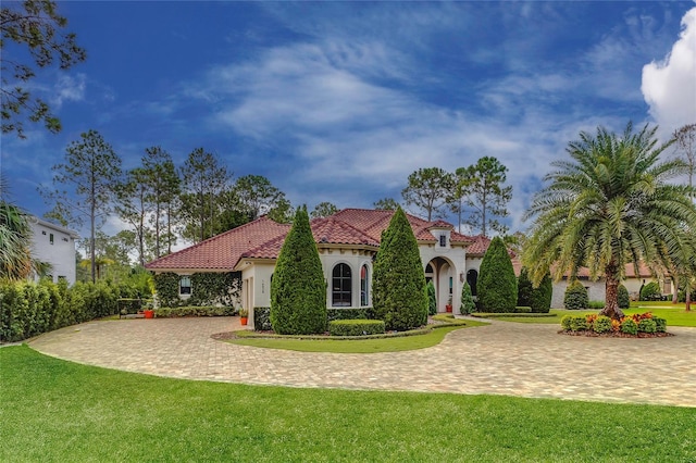 view of front of house featuring stucco siding, a tile roof, decorative driveway, and a front yard