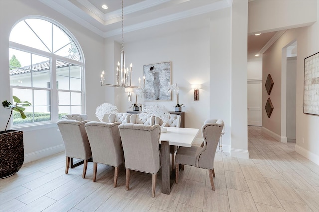 dining area with a notable chandelier, baseboards, a raised ceiling, and crown molding