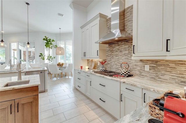 kitchen featuring visible vents, backsplash, appliances with stainless steel finishes, a sink, and wall chimney exhaust hood