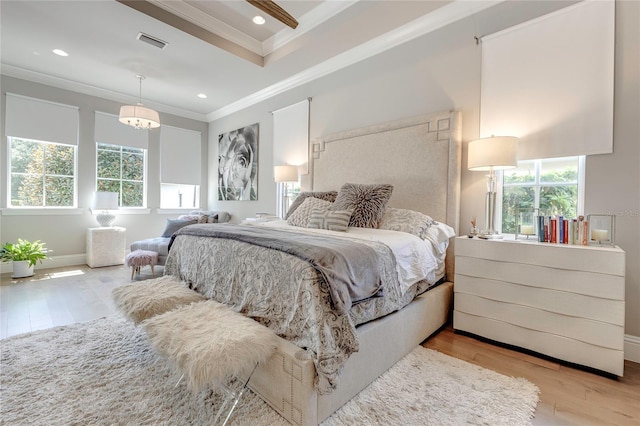 bedroom with baseboards, visible vents, wood finished floors, crown molding, and recessed lighting