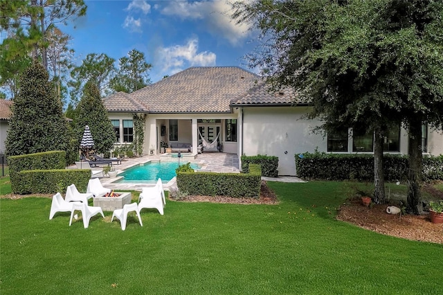 rear view of property featuring an outdoor pool, a lawn, a tiled roof, a patio area, and stucco siding