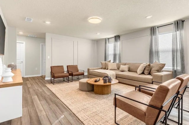 living room with light wood-type flooring, a wealth of natural light, and a textured ceiling