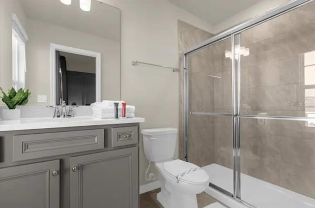 bathroom with a shower with door, vanity, and toilet