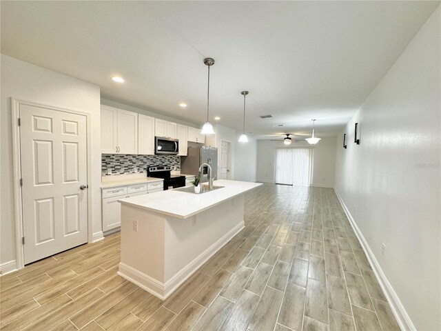 kitchen featuring ceiling fan, tasteful backsplash, sink, a center island with sink, and stainless steel appliances