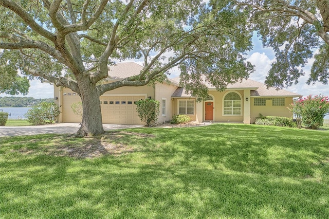 view of front of house with a garage, a water view, a front lawn, and stucco siding