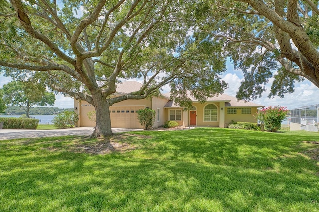 view of front facade with driveway, a water view, an attached garage, a front lawn, and stucco siding