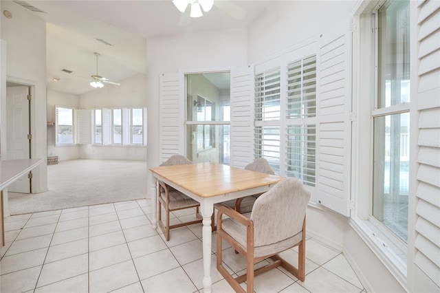 dining room with lofted ceiling, light tile patterned floors, ceiling fan, and light colored carpet