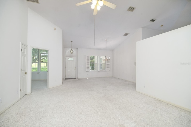 unfurnished living room with high vaulted ceiling, light colored carpet, visible vents, and ceiling fan with notable chandelier