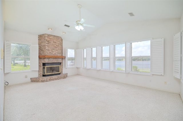 unfurnished living room featuring a fireplace, a water view, carpet flooring, visible vents, and vaulted ceiling