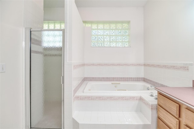 bathroom with a stall shower, a bath, and vanity