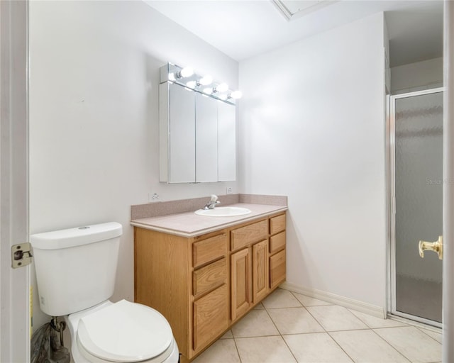 bathroom featuring toilet, a stall shower, vanity, baseboards, and tile patterned floors