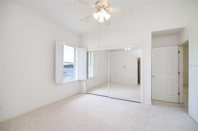 unfurnished bedroom with light carpet, ceiling fan, vaulted ceiling, and a closet