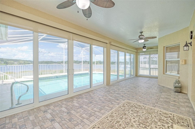 unfurnished sunroom with a water view and ceiling fan