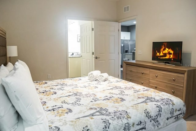 bedroom featuring stainless steel refrigerator with ice dispenser and connected bathroom