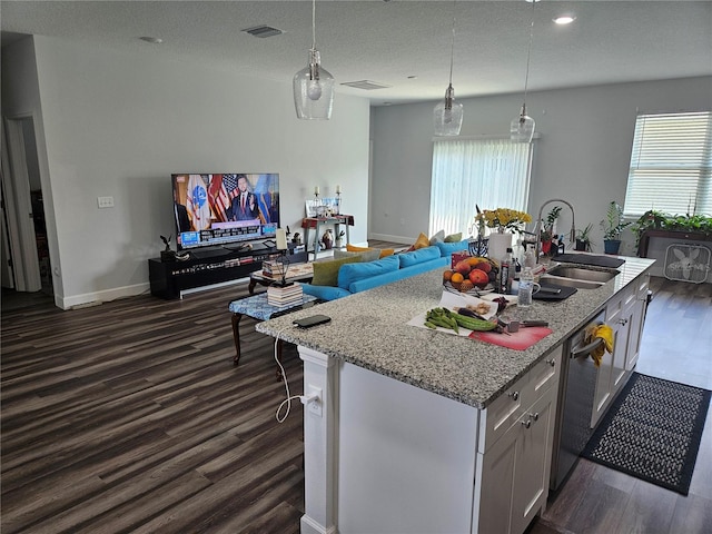 kitchen with decorative light fixtures, dishwasher, sink, white cabinets, and a kitchen island with sink