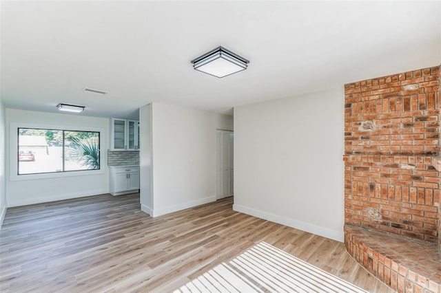 unfurnished living room featuring hardwood / wood-style flooring and brick wall