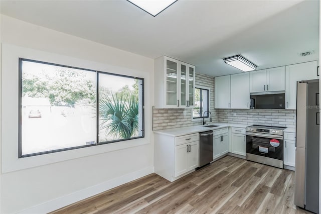 kitchen with white cabinets, tasteful backsplash, light hardwood / wood-style flooring, and appliances with stainless steel finishes