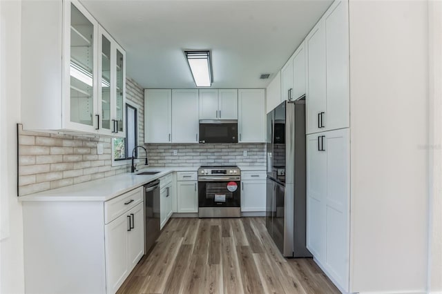 kitchen with sink, stainless steel appliances, light hardwood / wood-style floors, and white cabinetry