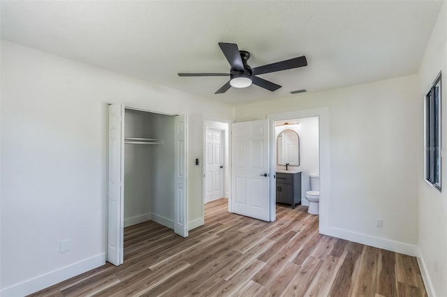 unfurnished bedroom featuring sink, wood-type flooring, a closet, ceiling fan, and ensuite bathroom