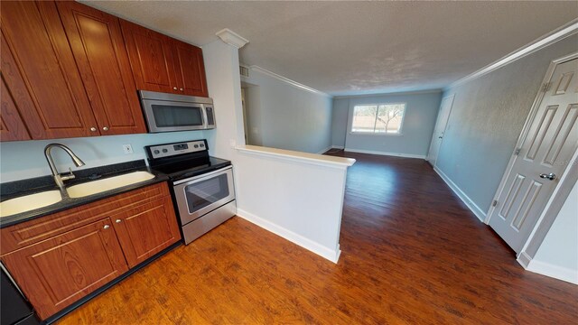 kitchen with crown molding, dark wood-type flooring, and stainless steel appliances