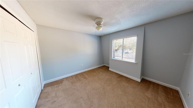 unfurnished bedroom with baseboards, ceiling fan, a textured ceiling, carpet flooring, and a closet