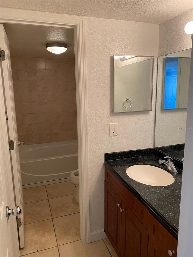 full bathroom featuring vanity, tile patterned flooring, a textured ceiling, tiled shower / bath, and toilet