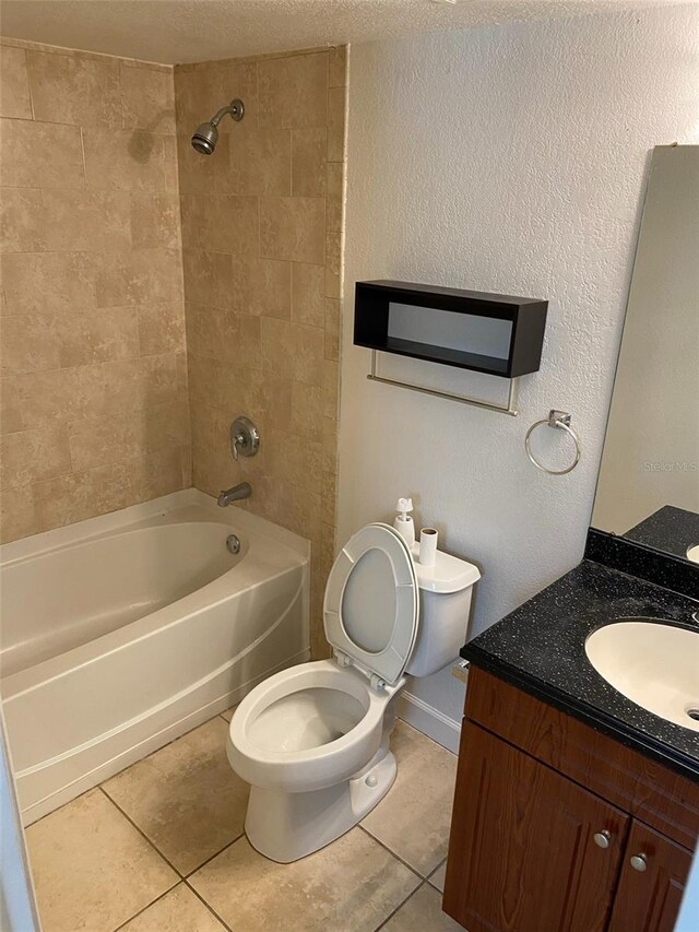 full bathroom with tile patterned floors, toilet, tiled shower / bath, and vanity