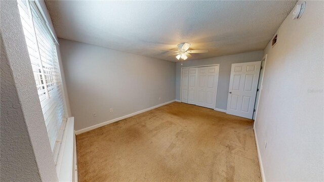 unfurnished bedroom with ceiling fan, a closet, and light carpet