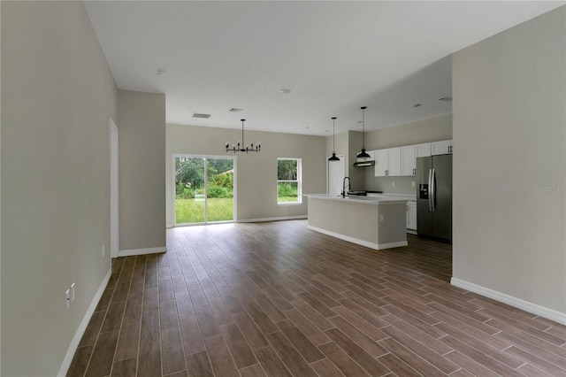 unfurnished living room featuring sink, dark wood-type flooring, and a notable chandelier