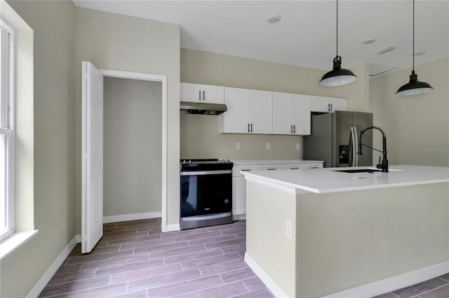 kitchen with appliances with stainless steel finishes, decorative light fixtures, sink, white cabinets, and a kitchen island