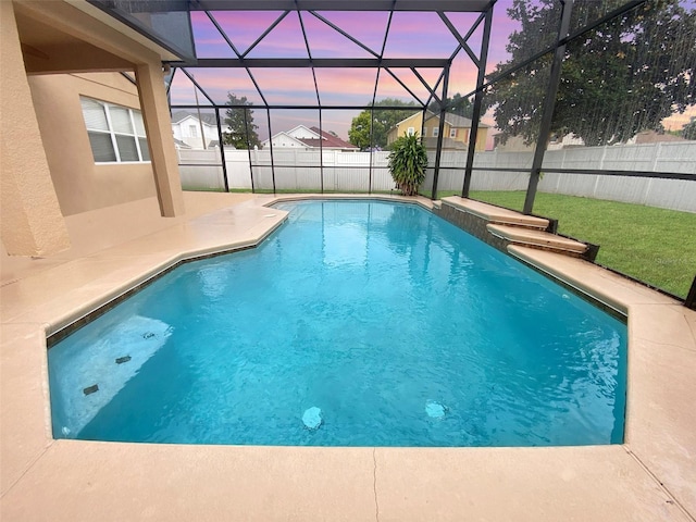 pool at dusk with a lanai and a patio area