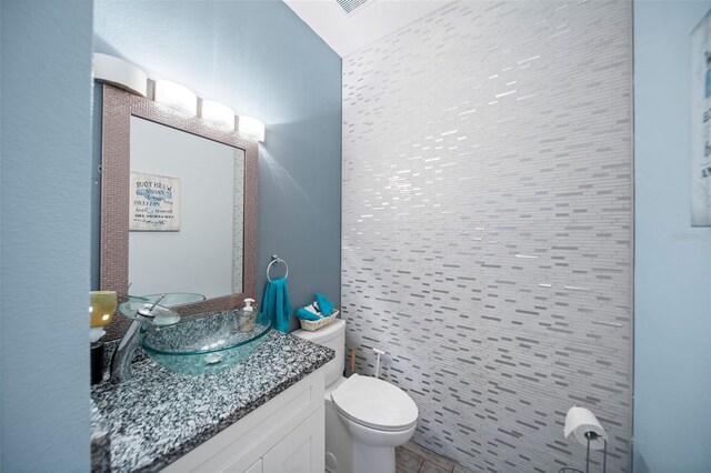 bathroom with tile walls, vanity, and toilet