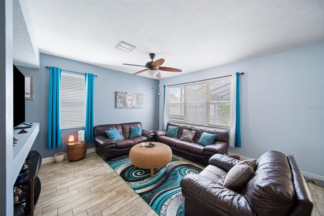 living room with ceiling fan, a textured ceiling, and light hardwood / wood-style flooring