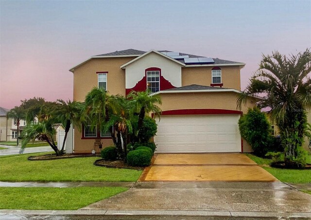 view of front facade with a yard, solar panels, and a garage