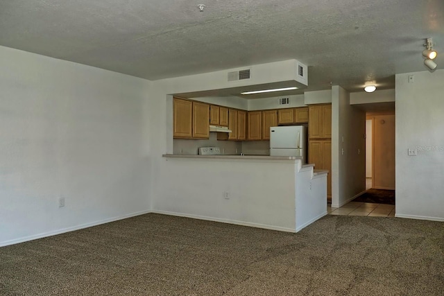 kitchen featuring kitchen peninsula, a textured ceiling, light carpet, and white refrigerator