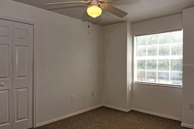 interior space featuring dark colored carpet, ceiling fan, and a closet