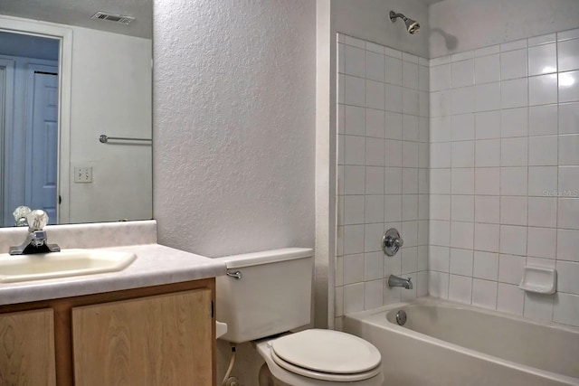 full bathroom featuring tiled shower / bath, vanity, and toilet