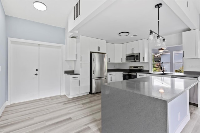 kitchen with white cabinets, appliances with stainless steel finishes, pendant lighting, and sink