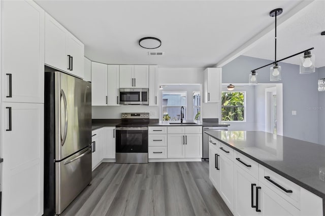 kitchen with hardwood / wood-style floors, sink, decorative light fixtures, white cabinetry, and stainless steel appliances