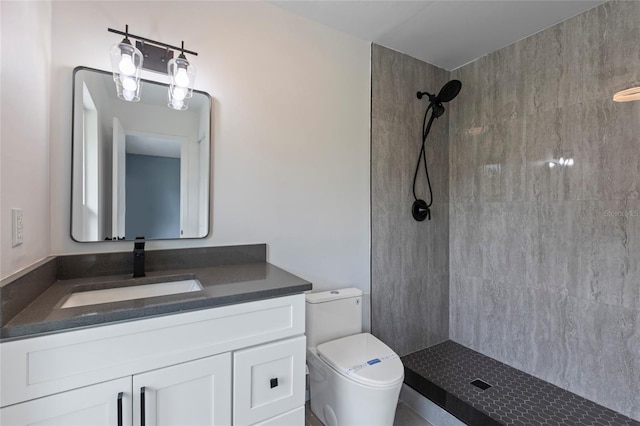 bathroom with tiled shower, vanity, and toilet