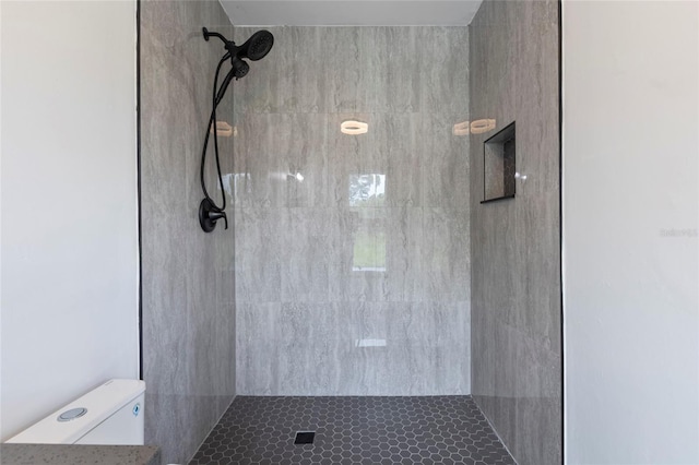 bathroom with a tile shower and toilet