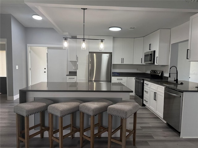 kitchen with sink, dark wood-type flooring, decorative light fixtures, white cabinets, and appliances with stainless steel finishes